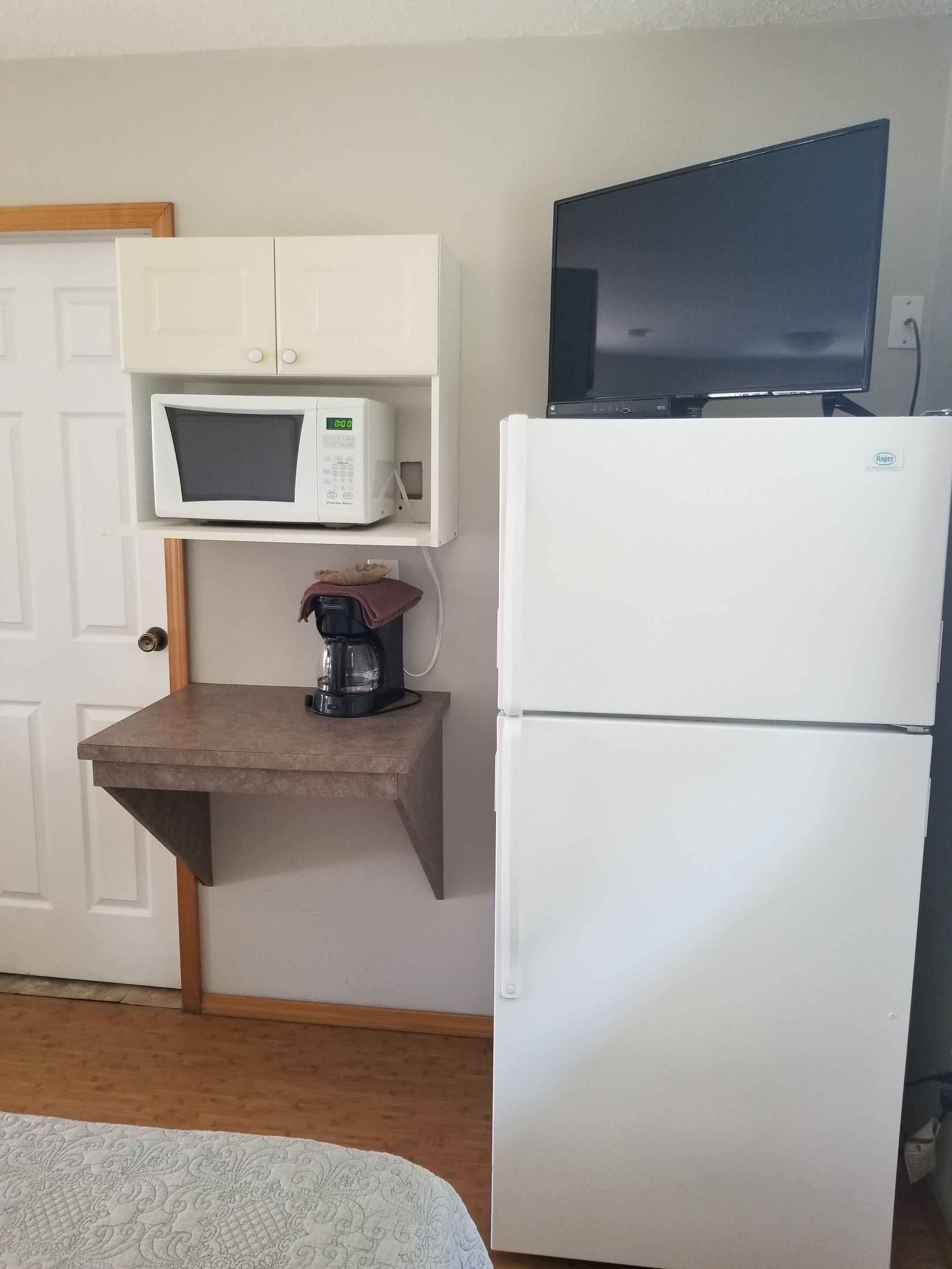 A compact kitchenette with a microwave, a coffee maker, and a refrigerator.