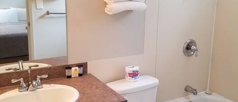 A bathroom with a sink, toilet, and bathtub. There are towels hanging on the wall and a shower curtain.