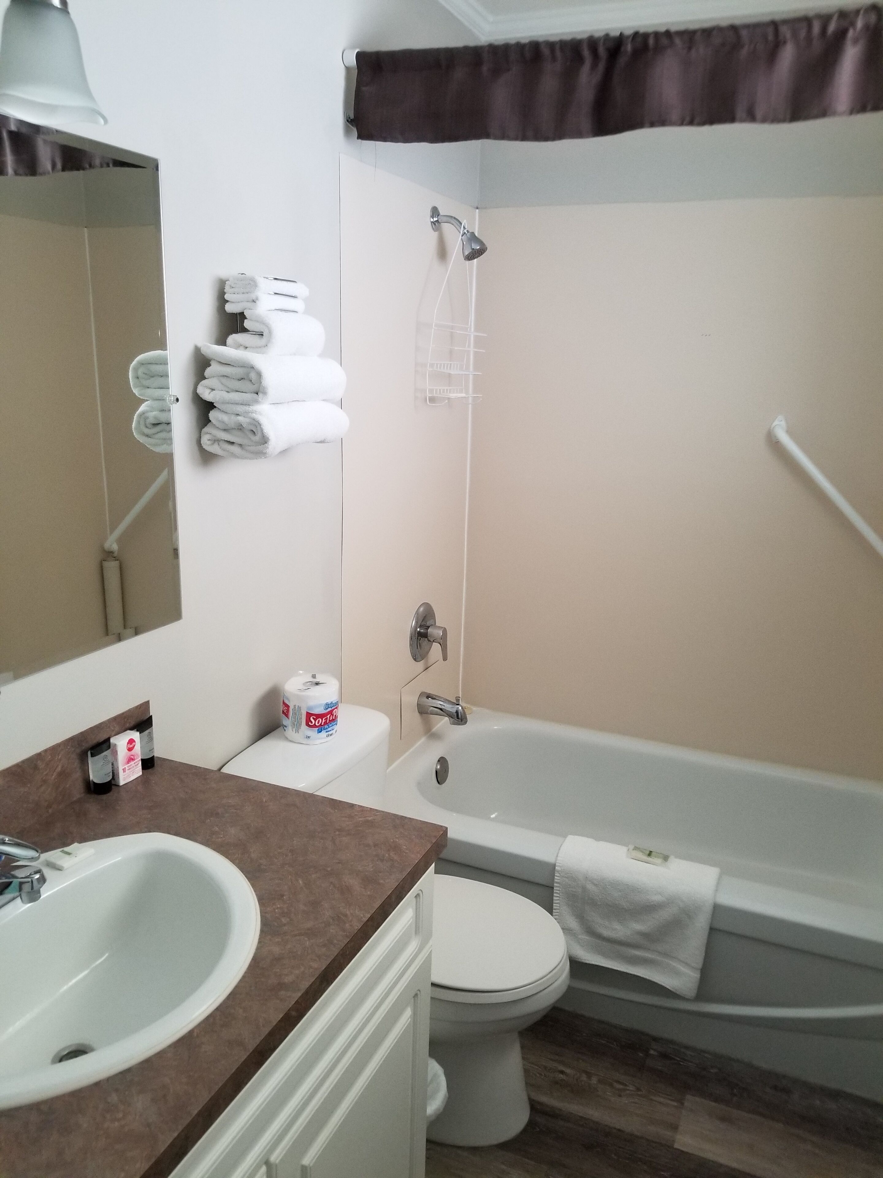 Un baño con lavamanos, inodoro y bañera. Hay toallas y artículos de aseo en la encimera.