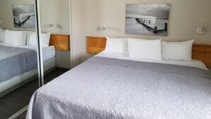 Ein Hotelzimmer mit zwei Betten, einem großen Spiegel und zwei Wandleuchten.