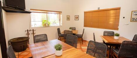 Un comedor con una mesa de madera, sillas de mimbre y un ventilador de techo.