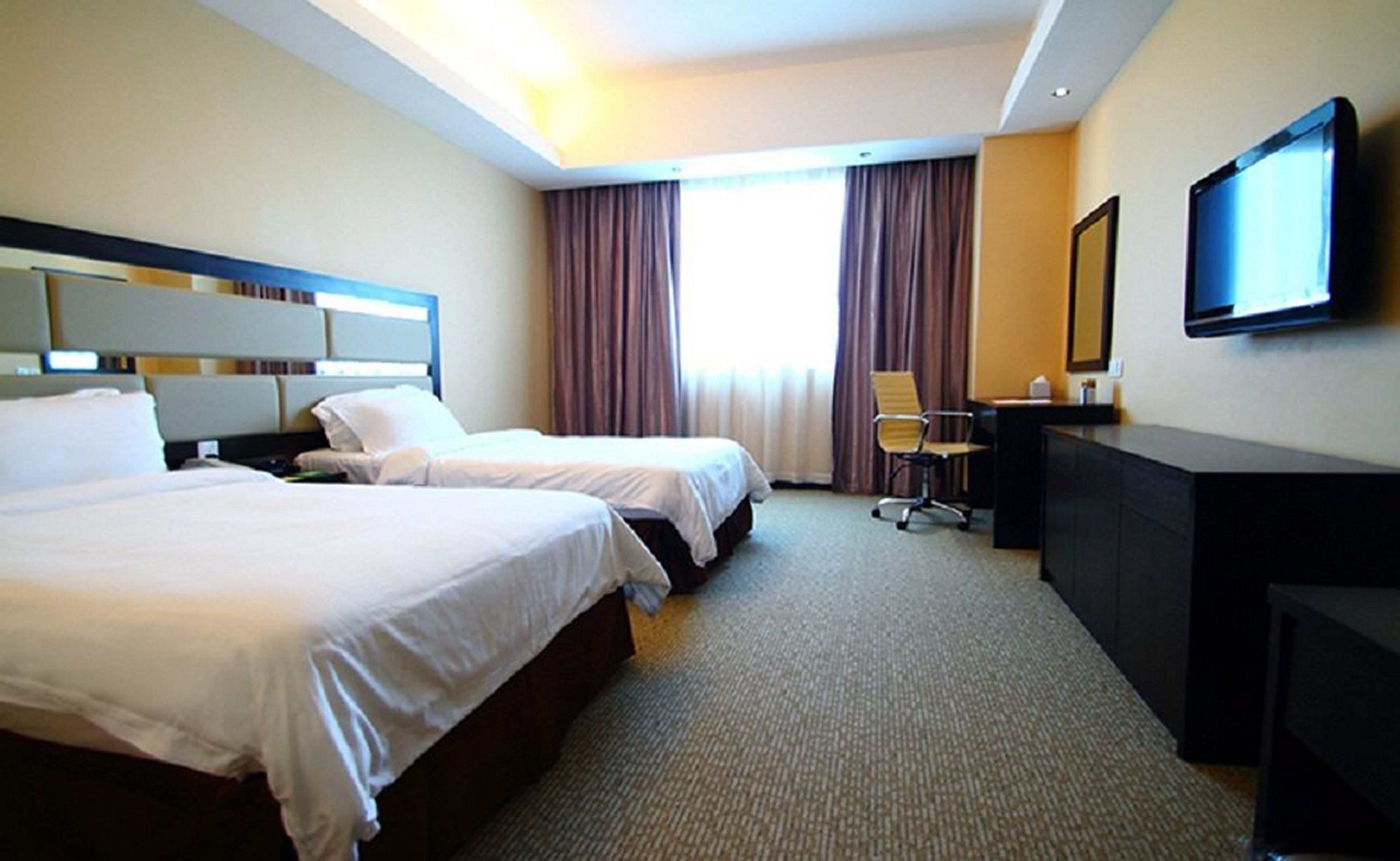 Une chambre d’hôtel avec deux lits, un bureau, une chaise et un téléviseur.