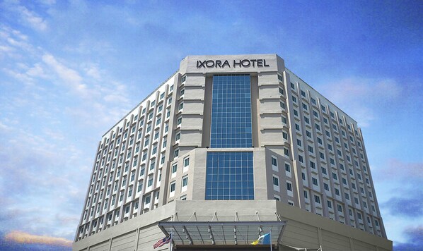 A tall, modern hotel building with a prominent glass facade and the name "IXORA HOTEL" at the top. - Ixora Hotel (Perai)