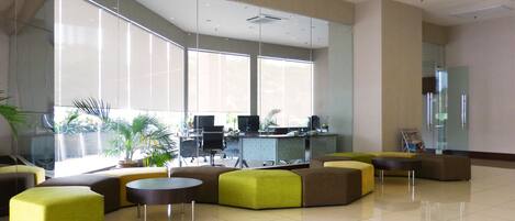 Un vestíbulo amplio con ventanas grandes, una mesa de recepción y una disposición moderna de asientos.