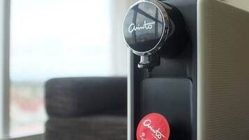 Une machine à café avec plusieurs dosettes de café, posée sur une table près d’une fenêtre.