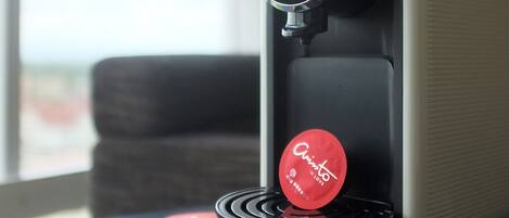 A coffee machine with multiple coffee pods on a table near a window.