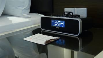 Un reloj digital muestra las 3:54 en una mesita de noche en una habitación de hotel.
