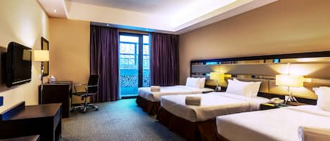 Habitación de hotel con dos camas, un escritorio, una silla, un televisor y una ventana con cortinas.