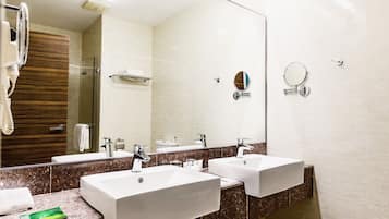 Un baño moderno con dos lavamanos, un espejo grande y un secador de pelo.