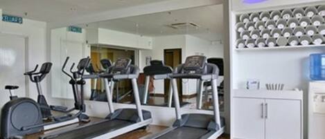 A gym with treadmills, stationary bikes, and a water dispenser.