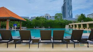 A poolside area with lounge chairs and a gazebo. A tall building is visible in the background. - The Leela Resort & Spa Pattaya (Pattaya)