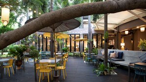 An outdoor dining area with tables and chairs, umbrellas, and a seating area with a sofa. - The Leela Resort & Spa Pattaya (Pattaya)