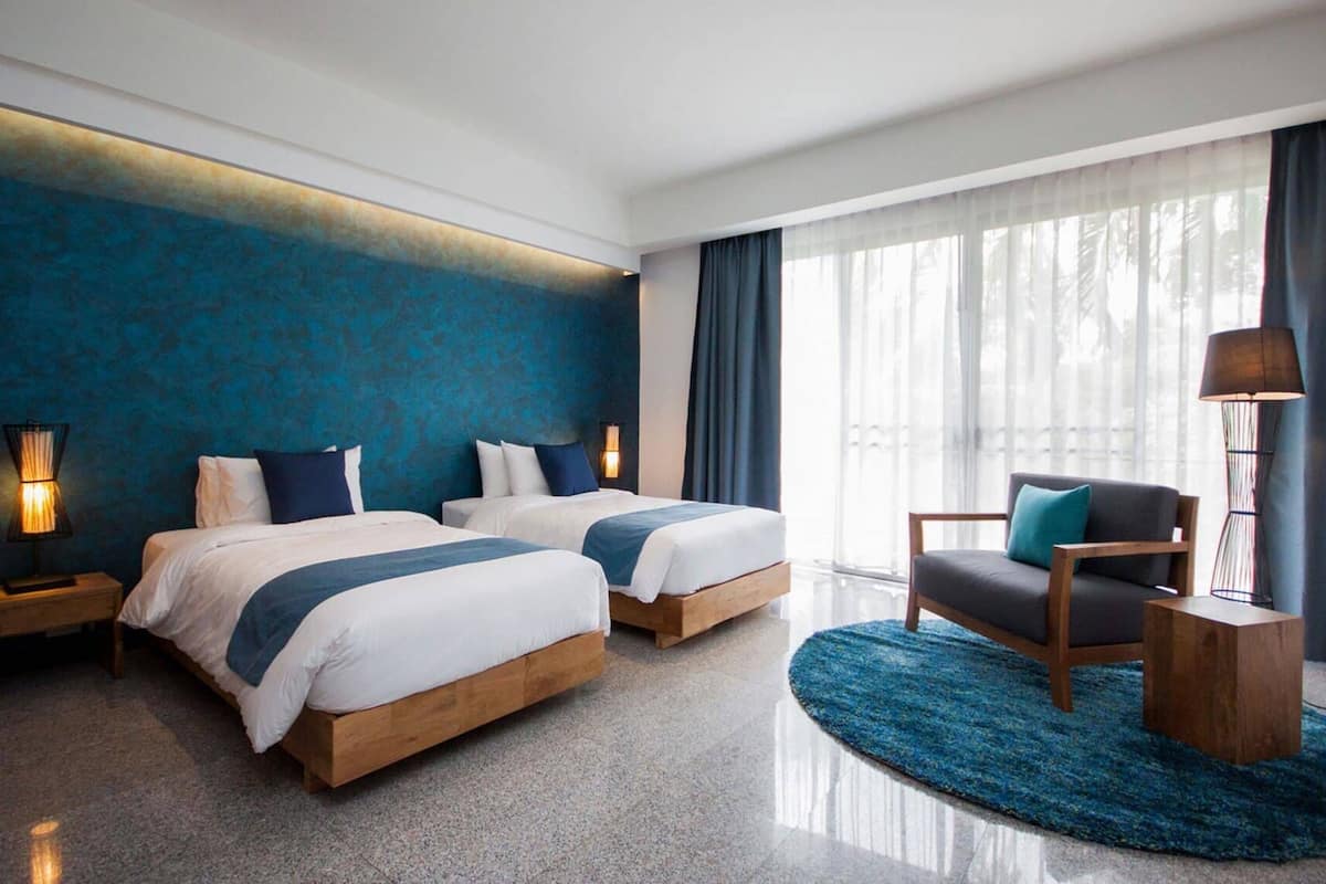 Ein modernes Hotelzimmer mit zwei Betten, einer Sitzecke und großen Fenstern.
