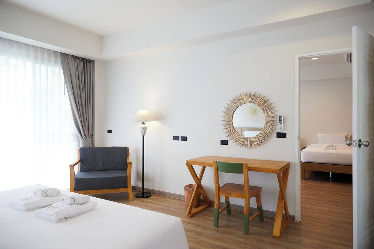 Ein Hotelzimmer mit Bett, Schreibtisch, Stuhl, Lampe und Spiegel.