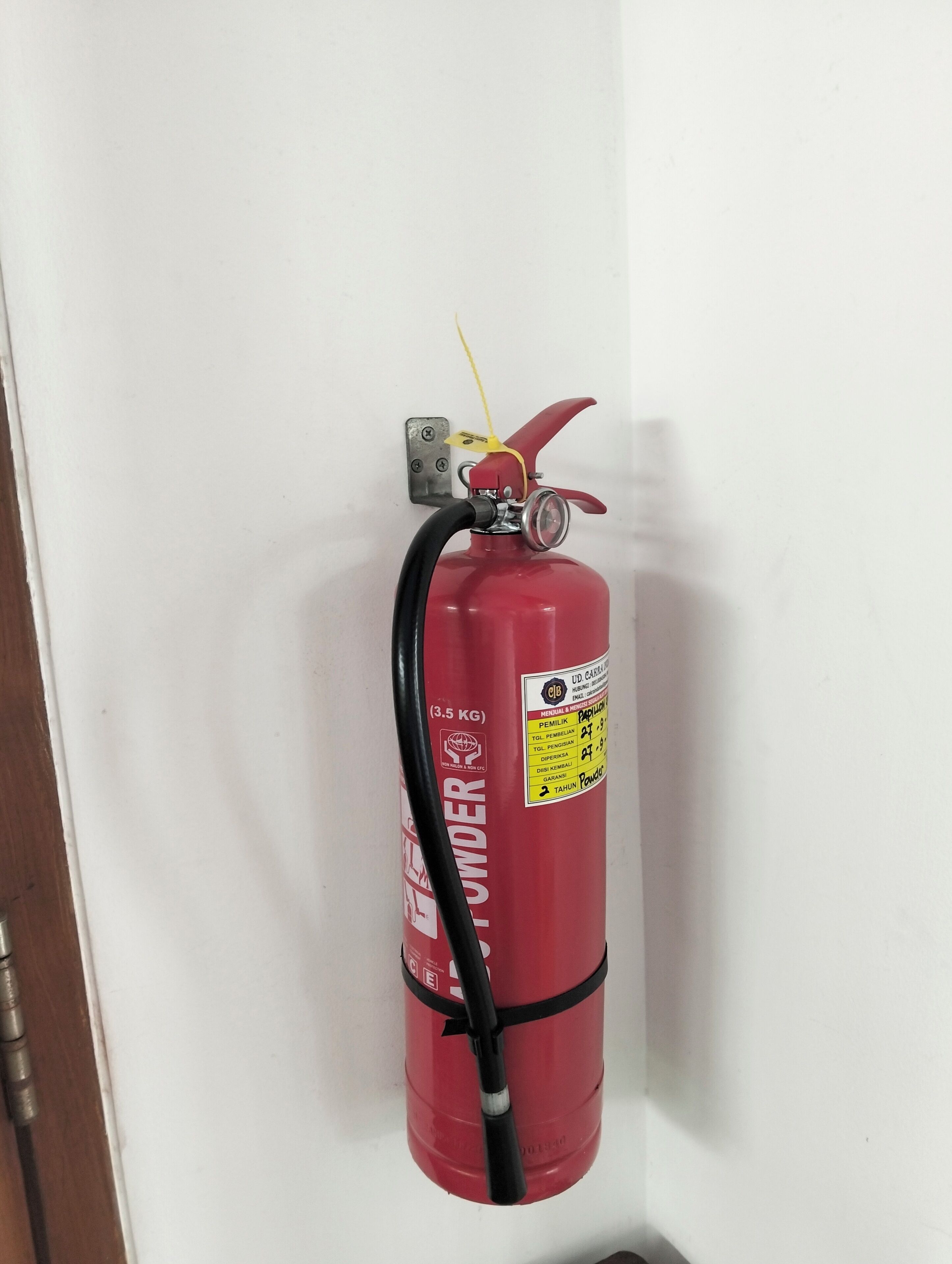 A red fire extinguisher mounted on a white wall.