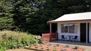 A small building with a porch, a red fence, and a garden with various plants and flowers. - Twelve Apostles Motel & Country Retreat (Princetown)