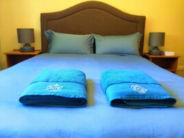 Una cama bien hecha con dos toallas dobladas y un cabecero de madera.