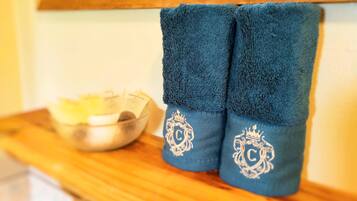 A pair of blue towels with embroidered monograms on a wooden surface next to a bowl.