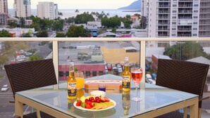A balcony with a glass table set with drinks, a fruit plate, and a box of tissues. - Cairns Central Plaza Apartment Hotel (Cairns)