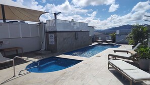 A rooftop pool area with a clear view of the mountains, lounge chairs, and a pool safety sign. - Cairns Central Plaza Apartment Hotel (Cairns)