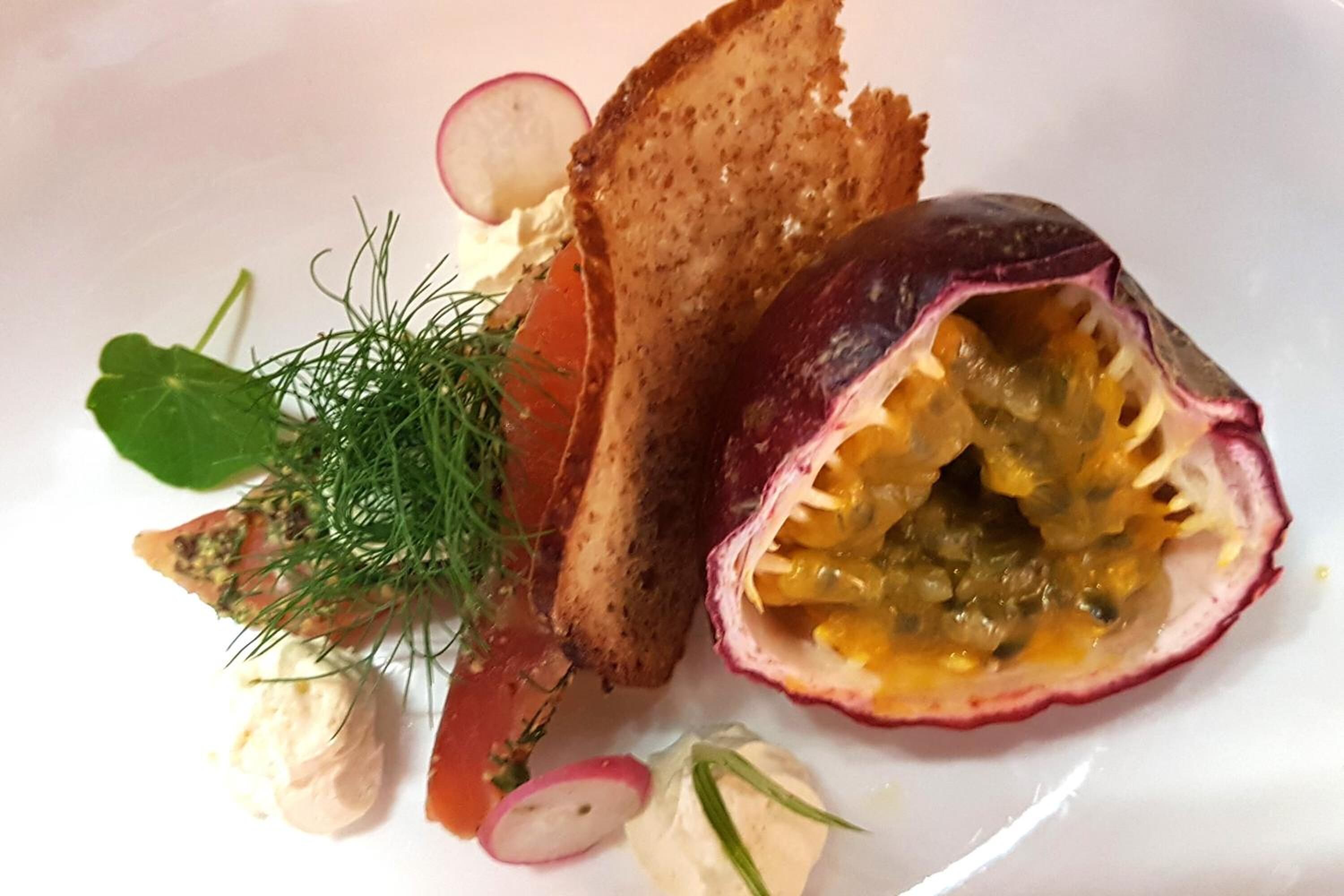Une assiette avec la moitié d’un fruit de la passion coupé, des tranches de pain grillé et une cuillère de crème.