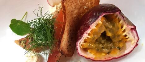Une assiette avec la moitié d’un fruit de la passion coupé, des tranches de pain grillé et une cuillère de crème.