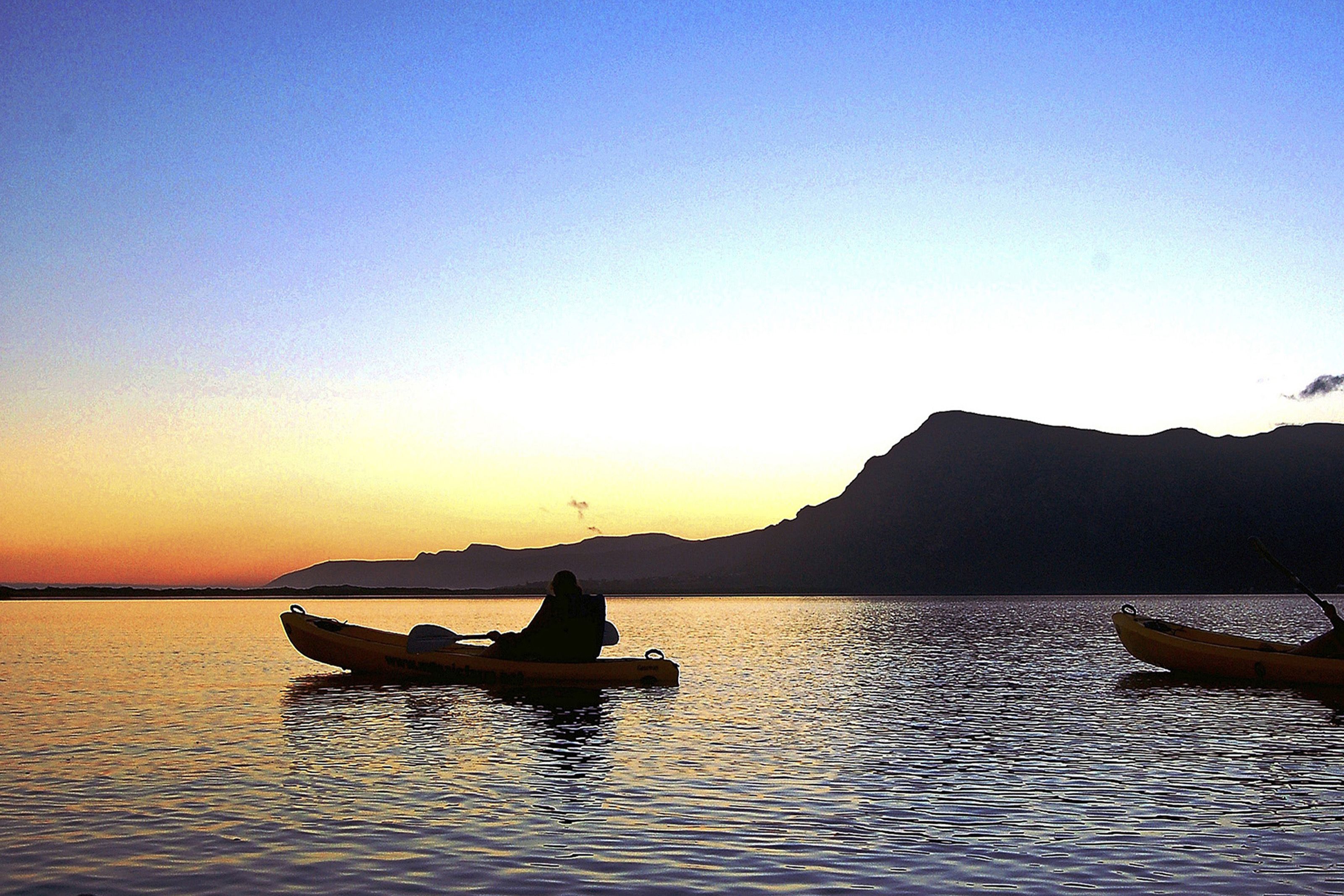 Un lac paisible au coucher du soleil, avec deux kayaks.