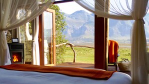 Un dormitorio con cama, chimenea y vistas a las montañas.
