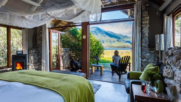 Un dormitorio con chimenea de piedra, una cama y vistas a un paisaje montañoso.