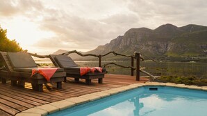 Zona de piscina con sillones de descanso y vistas a las montañas.