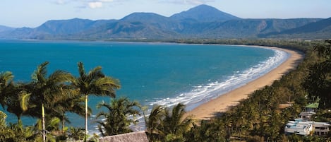 Una playa cerca, arena blanca, sillas reclinables de playa, sombrillas