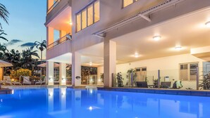 A hotel with a swimming pool, outdoor seating, and a covered area with plants. - Silkari Reflections of Port Douglas (Port Douglas)