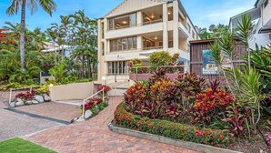 A two-story hotel with a balcony on the second floor, surrounded by tropical plants and a brick pathway. - Silkari Reflections of Port Douglas (Port Douglas)