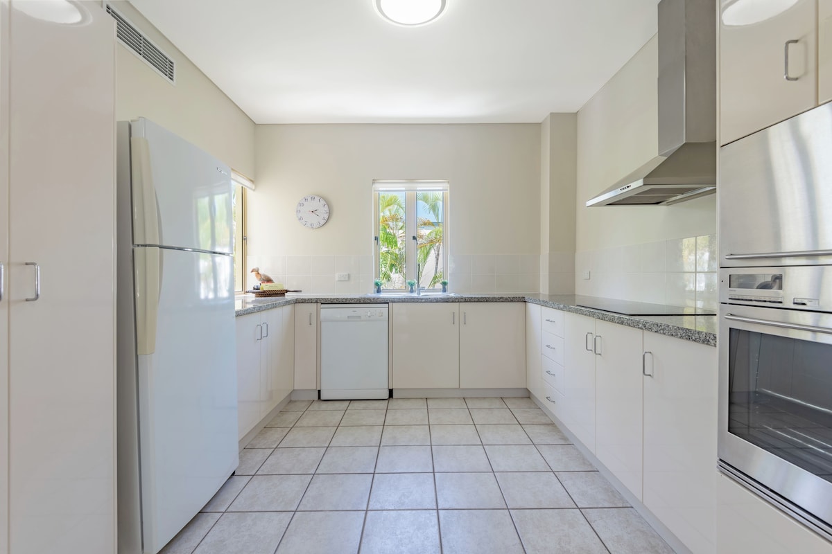 A modern kitchen with white cabinets, a stainless steel refrigerator, an oven, and a dishwasher.