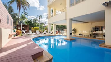 Una piscina al aire libre, sombrillas, sillones reclinables de piscina