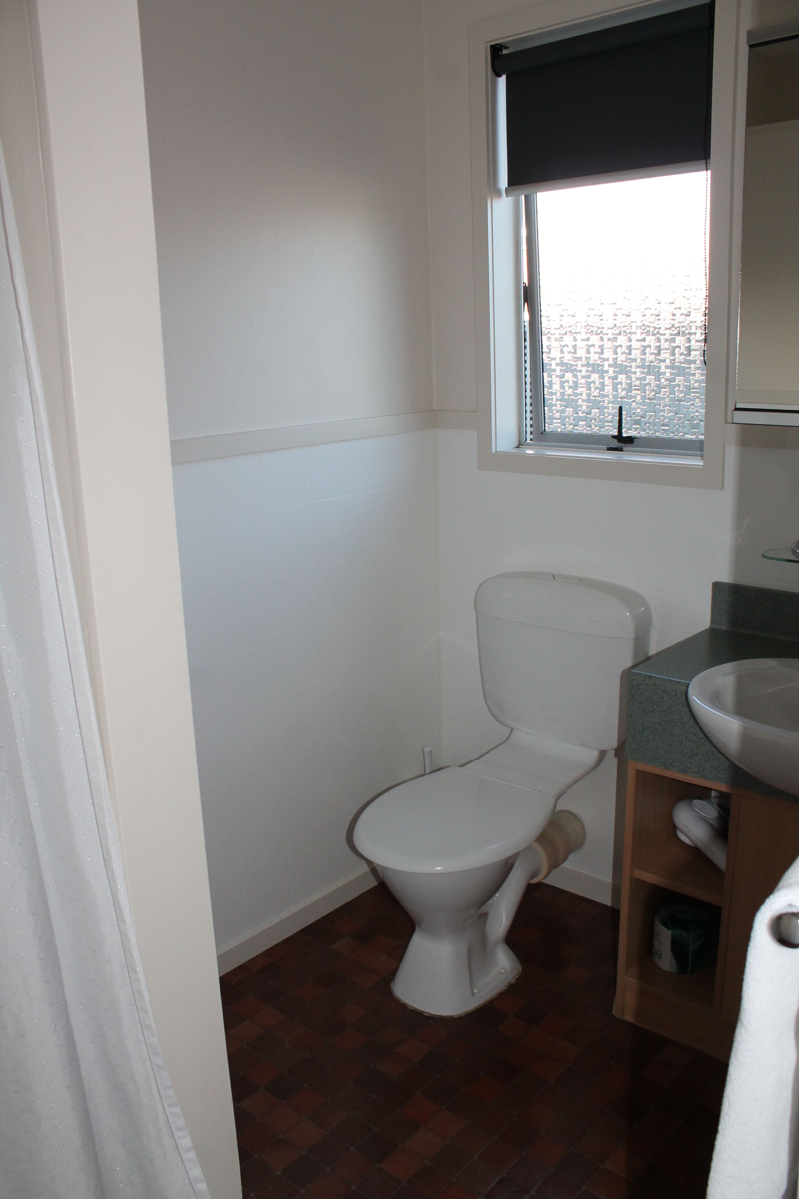 Een badkamer met een toilet, een raam en een wastafel.