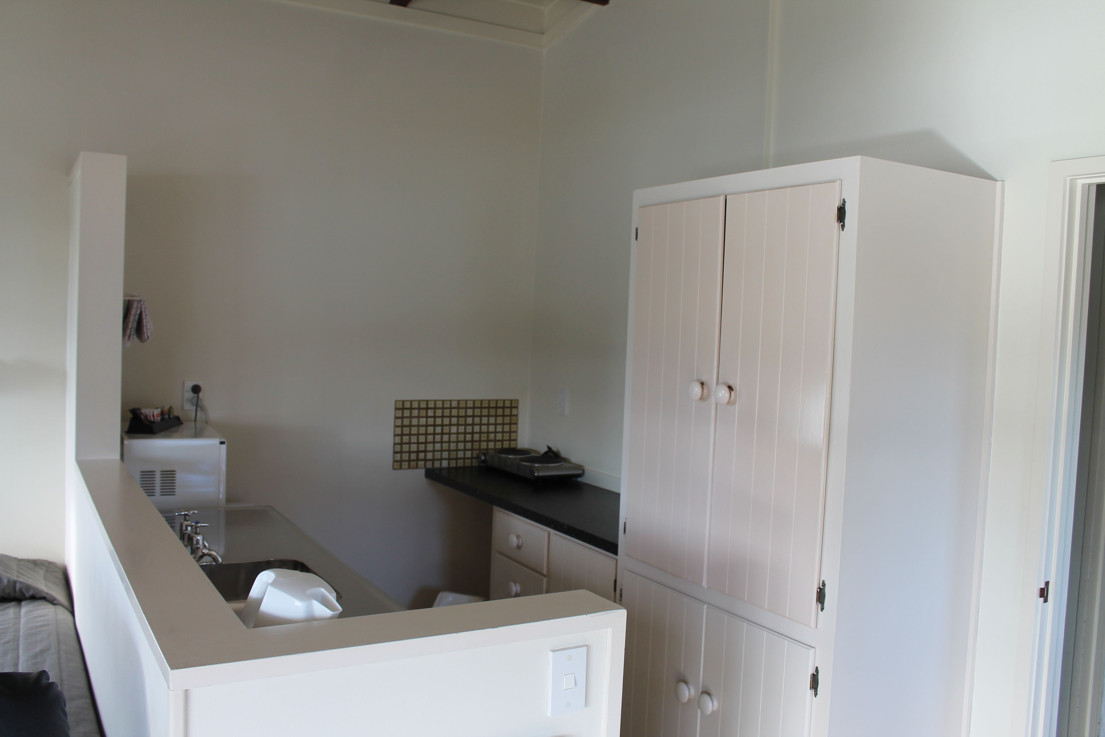 A compact kitchen with a sink, countertop, and a white cabinet.