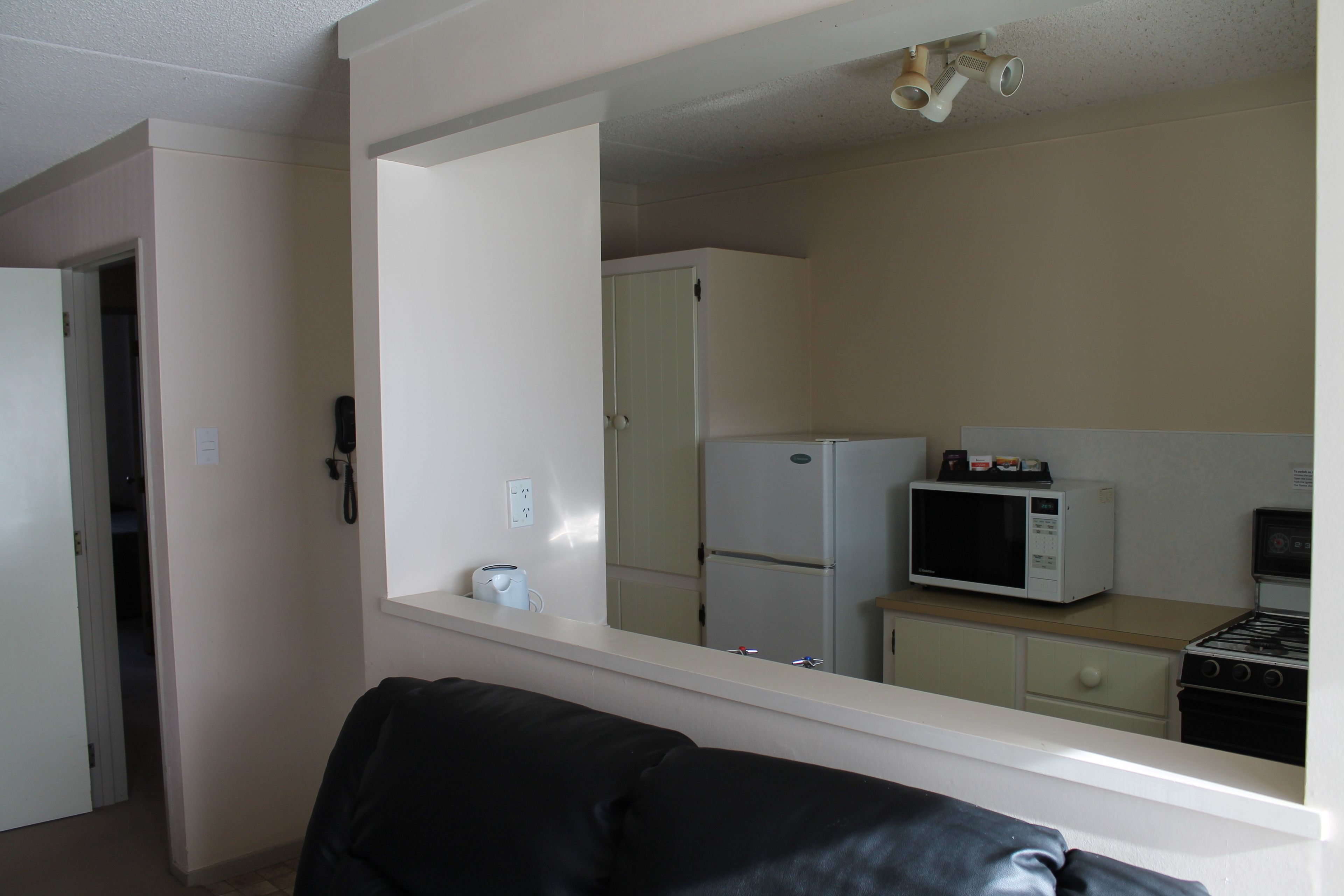 A compact living space with a kitchenette, a refrigerator, a microwave, and a stove.