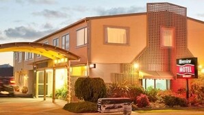 Un motel con un amplio toldo sobre la entrada, un cartel anunciador y jardines bien cuidados.