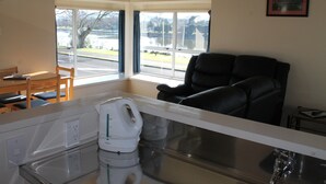 Una cocina moderna con horno integrado, cafetera y vistas a un lago a través de amplios ventanales.
