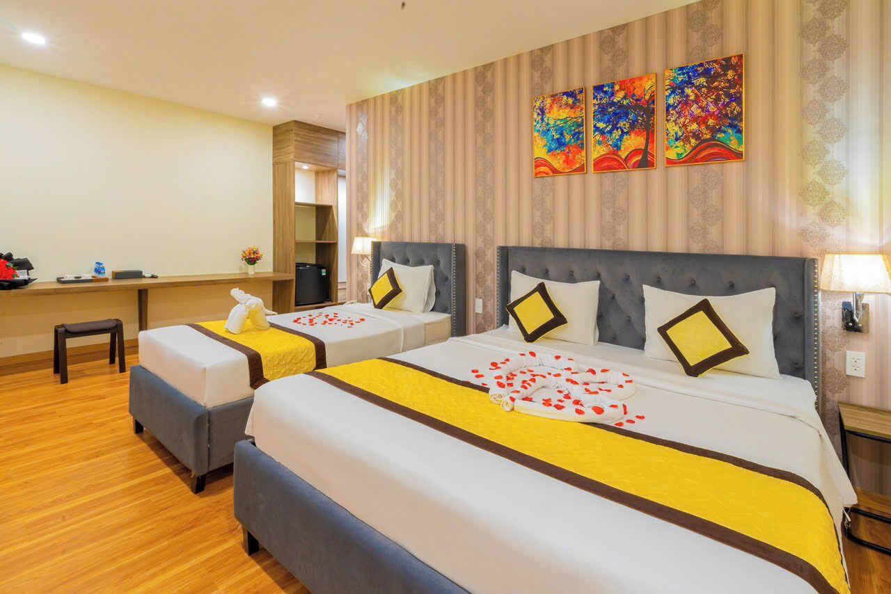 A hotel room with two beds, a desk, and a mirror.
