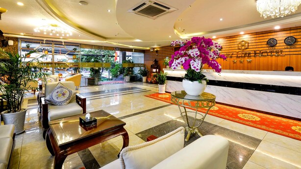 A hotel lobby with a reception desk, seating area, and decorative plants. - Happy Life Hotel (Ho Chi Minh City)