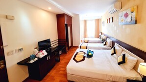 A hotel room with two beds, a desk with a laptop, a small table with toiletries, and a wall-mounted air conditioner. - Happy Life Hotel (Ho Chi Minh City)