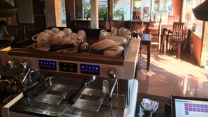 A coffee shop interior with a coffee machine, seating area, and large windows. - Otres Beach Resort (Sihanoukville)