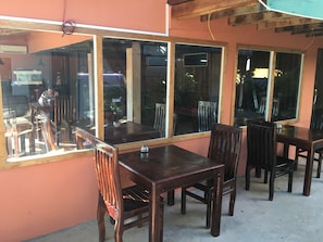 A dining area with wooden tables and chairs, large windows, and a concrete floor. - Otres Beach Resort (Sihanoukville)