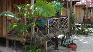 A wooden house with a red roof, surrounded by lush greenery and a sandy ground. - Otres Beach Resort (Sihanoukville)