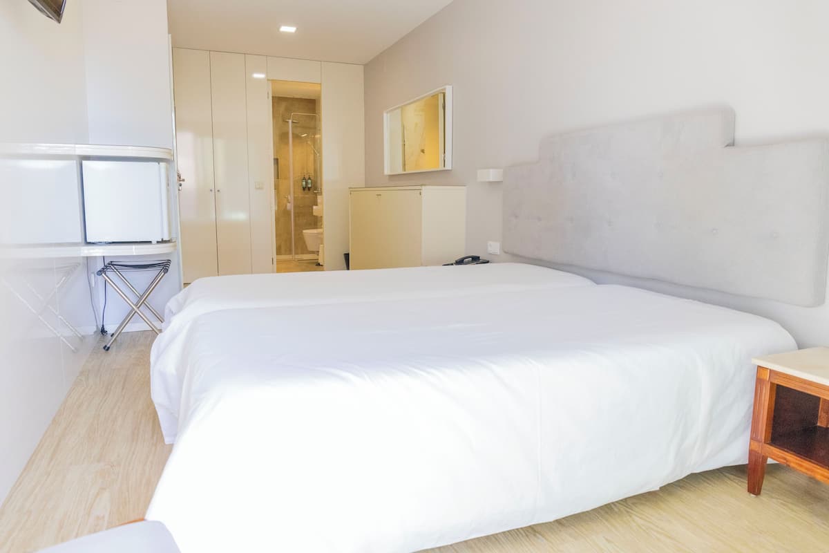 A hotel room with a large bed, a desk, and a wardrobe.