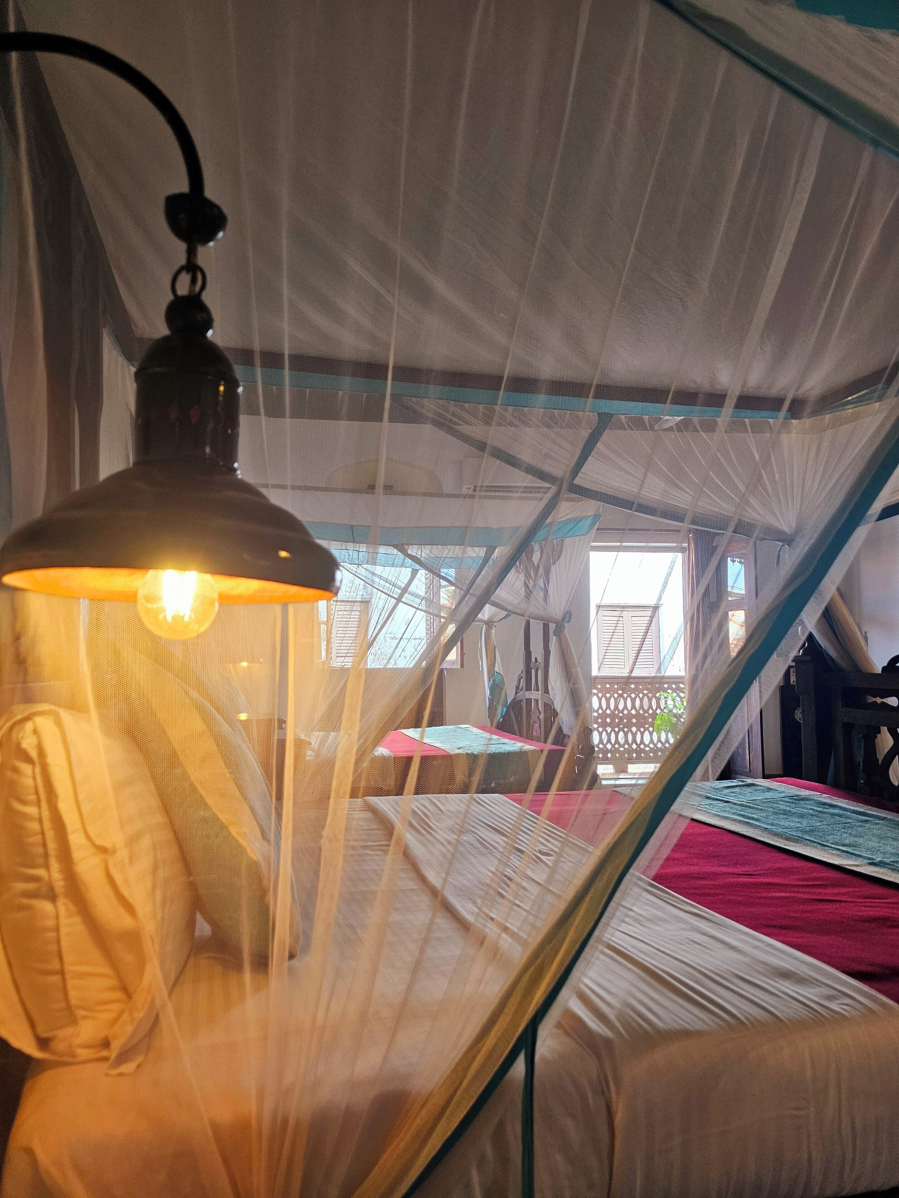 A tented room with a bed, a hanging light fixture, and a view of the outside.