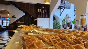 A buffet with waffles and various fruits and pastries.