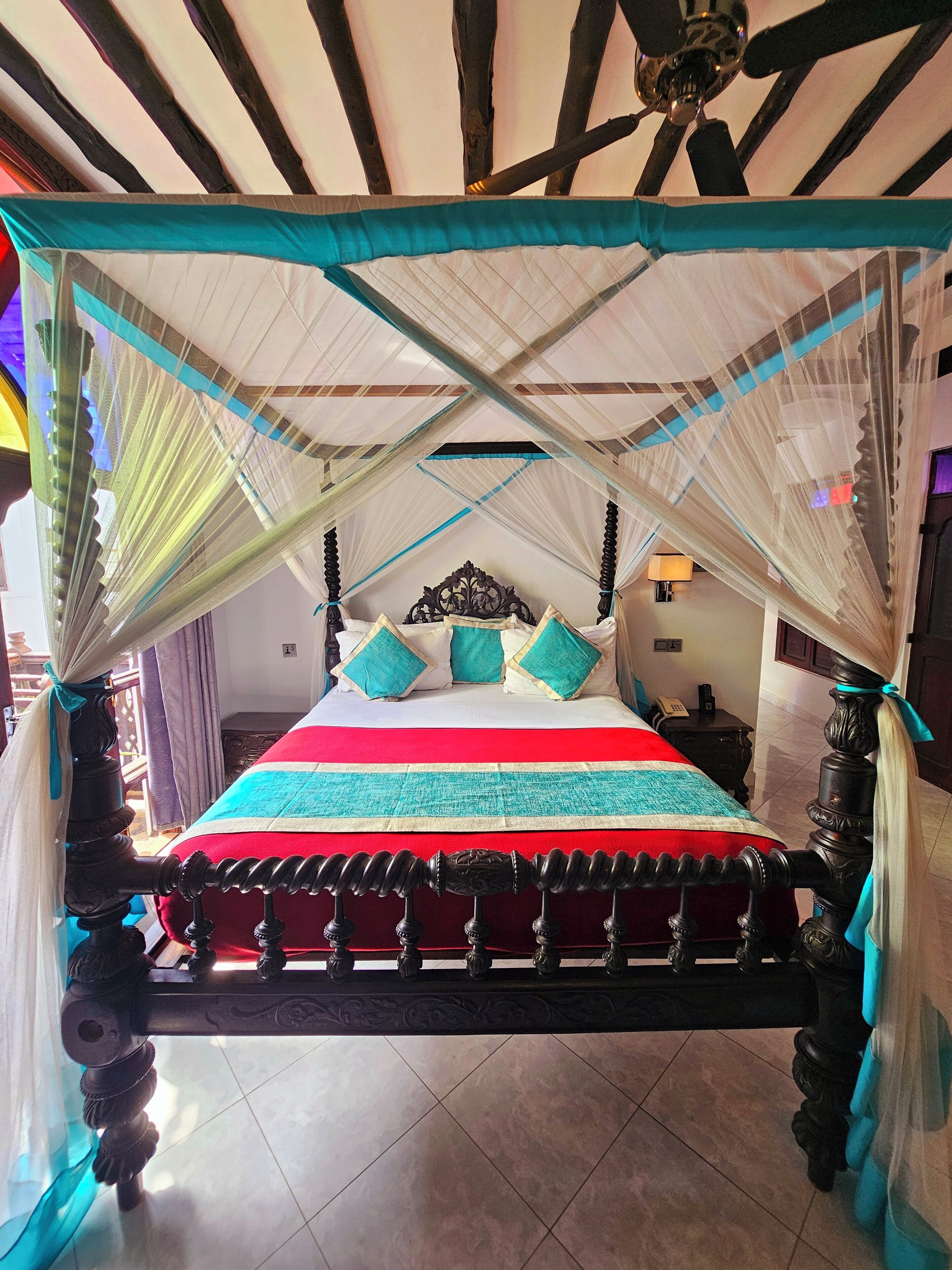 A bed with a canopy, a headboard, and a bedside table with a lamp.